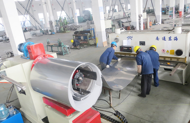 Workers operating industrial sheet metal processing machinery